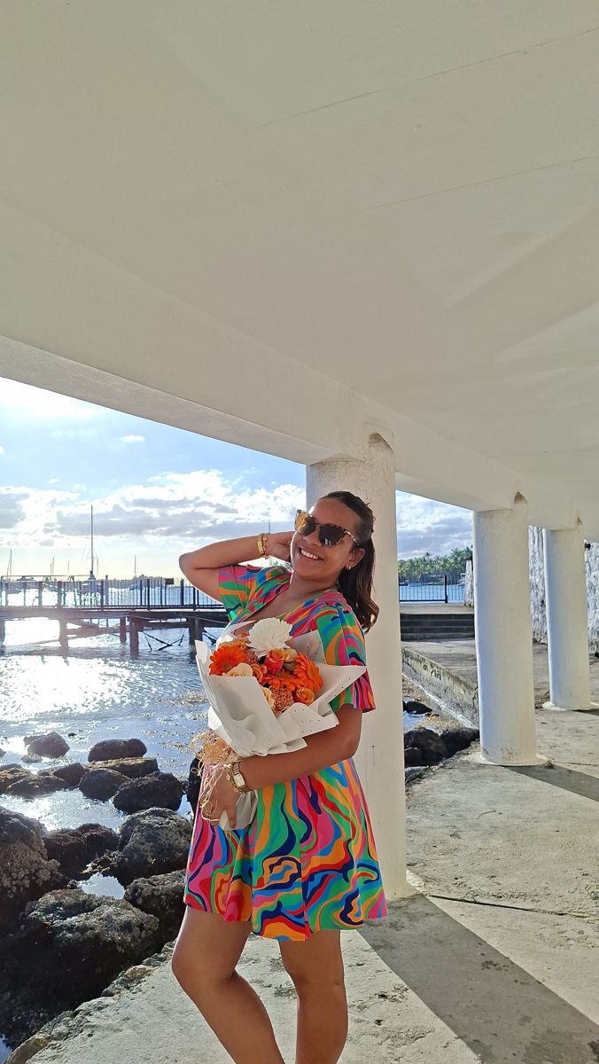 Une cliente au bord de la mer à Grand Baie avec un bouquet de gerberas et roses orange